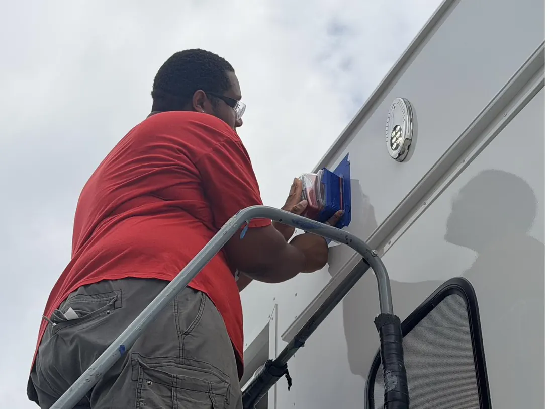 TreVince installing exterior lighting on the side of a mobile medical trailer